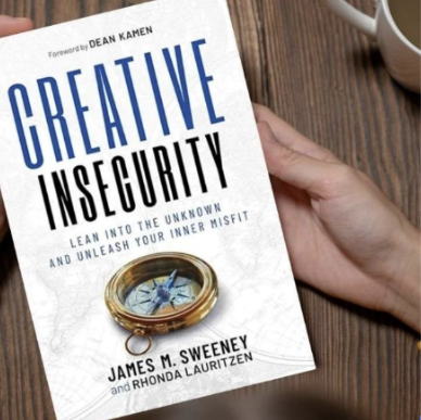 Creative Insecurity BOOOK A hand holding a book titled "Creative Insecurity," authored by James M. Sweeney and Rhonda Lauritzen. The book's subtitle emphasizes the use of insecurity as a tool for personal growth, with a compass symbol adding a metaphorical layer of navigating challenges.